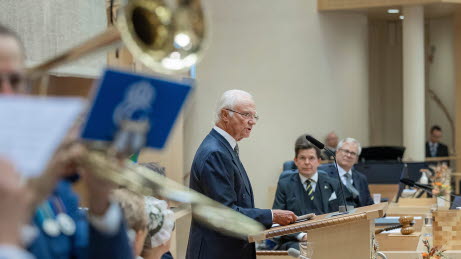 Kungen och talmannen vid talmanspodiet under riksmötets öppnande. I förgrunden en trumpet.