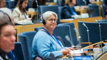 Kvinna sitter i kammaren och lyssnar på debatten