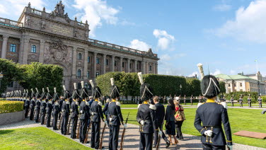 Riksdagsledamöter på väg in till riksdagshuset flankerade av Livgardet.