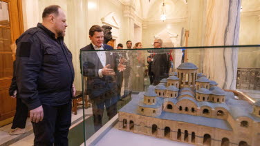 The two Speakers look at an exhibition of old buildings.