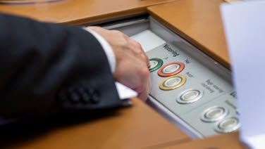 Person trycker på en röstknapp i sin bänk.