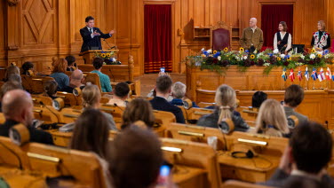 Talmannen står i talarstolen och deltagarna lyssnar.