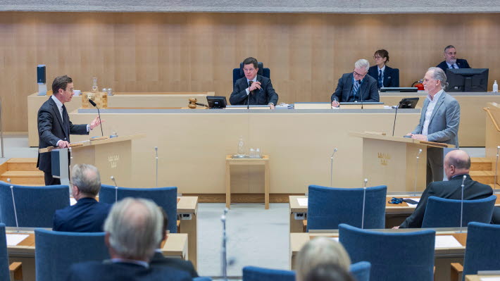 Statsminister Ulf Kristersson (M) och Daniel Helldén (MP) debatterar i kammaren. I bakgrunden syns talman Andreas Norlén.