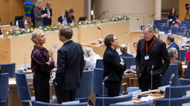 Fyra personer står upp i kammaren och pratar med varandra två och två.