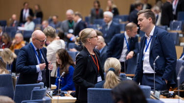 Sessionsdeltagare i kammaren småpratar med varandra.