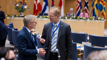 Två sessionsdeltagare pratar med varandra i kammaren.