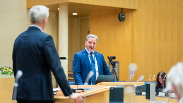 Två män debatterar i kammaren.