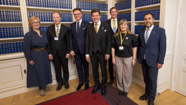 Gruppbild på sju personer i ett rum med böcker i bakgrunden.