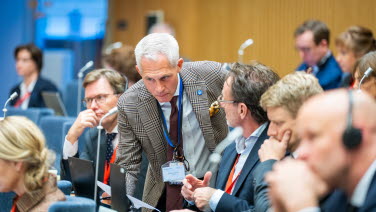 Delegat böjer sig fram över en annan delegat.