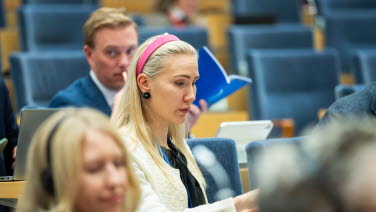 Kvinna sitter i publiken och följer debatten.