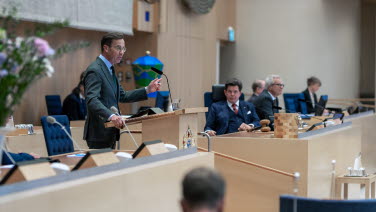 Statsminister Ulf Kristersson (M) står i talarstolen. Till höger talman Andreas Norlén.