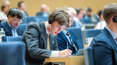 Ung delegat skriver i sin bänk. Han är koncentrerad.