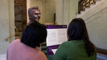 Two people looking at the bust of Olof Palme