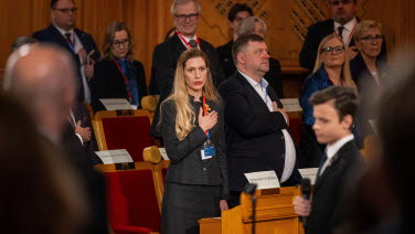The delegates standing up in the former Second Chamber. In the foreground a young boy.