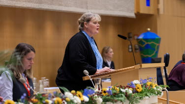 En kvinna står i talarstolen i kammaren.