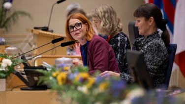 Kvinna i podiet lutar sig fram mot mikrofonen