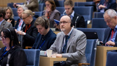 En man lyssnar på debatten. Han har hörlurar på sig.