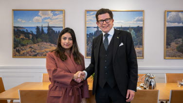 Partiledare Nooshi Dadgostar (V) skakar hand med talman Andreas Norlén. De tittar in i kameran.