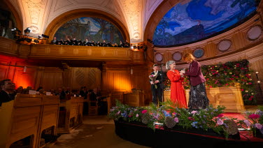 Pristagare i röd klänning tar emot pris på scenen i Andrakammarsalen.