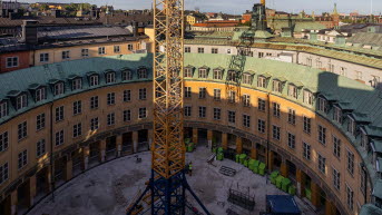 Foto taget ovanifrån på en rund innergård där det står en stor gul lyftkran.