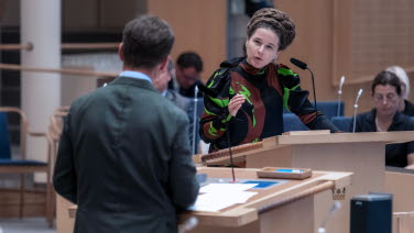 Miljöpartiets språkrör Amanda Lind debatterar med statsministern som har kameran vänd mot ryggen.