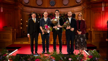 Fem personer står framme vid podiet i Andrakammarsalen