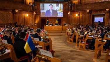 A man participating in the plenary meeting from the big screen. 