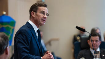 Statsminister Ulf Kristersson står vid en mikrofon. I bakgrunden syns talman Andreas Norlén.