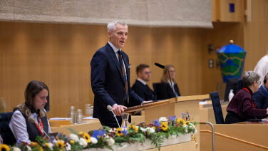 En man står i talarstolen i kammaren.