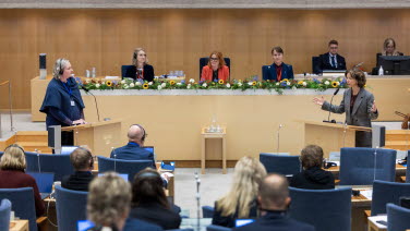 Kvinnor står vid varsin talarstol och debatterar.