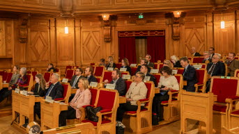 Åhörare sitter i träbänkar i Andrakammarsalen.