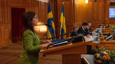 A woman delivers a speech from the rostrum in the former Second Chamber.