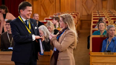 Talman Andreas Norlén samtalar med den isländska ledamoten Bryndís Haraldsdottír. I bakgrunden syns personer som sitter i bänkar i riksdagens förstakammarsal.