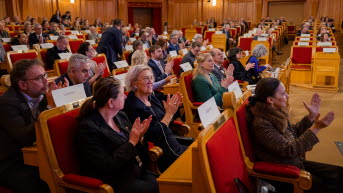 Sittande publik applåderar.