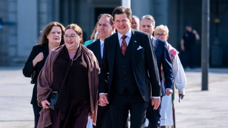 En grupp personer går mot kameran över ett torg. Längst fram går talmansparet.