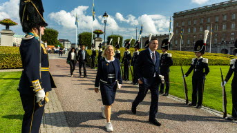 Uniformsklädda personer står på varsin sida om en gångväg där bland andra Magdalena Andersson går.