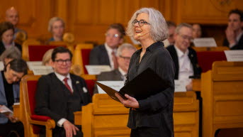 Eva Krutmeijer talar inför åskådare som syns i bakgrunden.