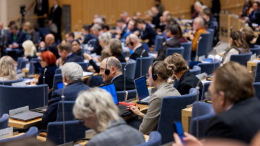 Delegater sitter och lyssnar under plenum.