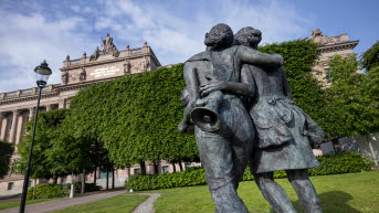 Konstverket med flickornas ryggar. Den ena flickan bär en megafon i ett band från axeln. 